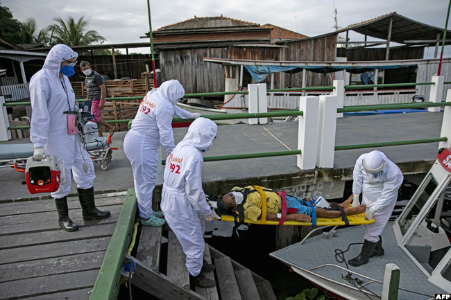  ealth personnel carry a man infected with the new coronavirus on a stretcher to be transferred on an ambulance boat from the community of ortel to a hospital in reves on arajo island ara state razil