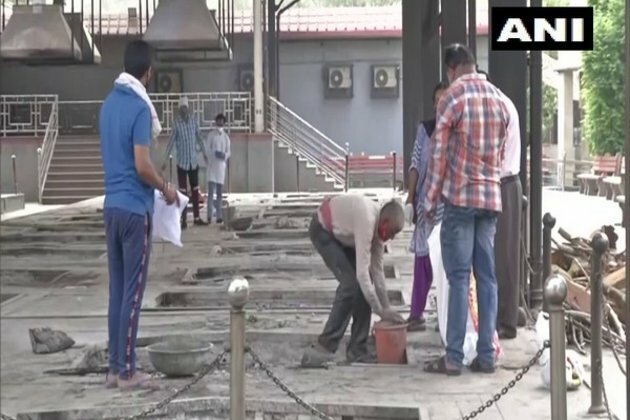 Workers at Nigambodh Ghat collect ashes of COVID victims