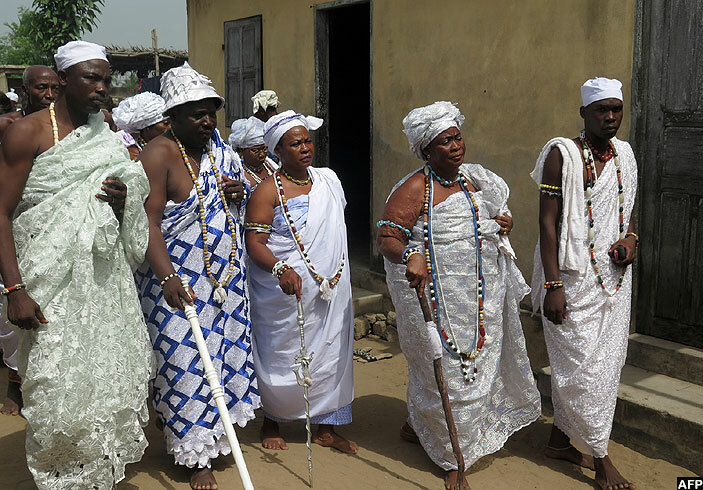  oodoo worshippers dressed in white robes and draped with long strings of multicoloured beads