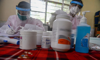 Health workers wearing ppe arrange medicines during a medical screening for covid 19 350x210