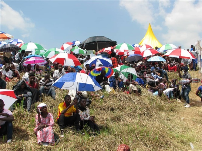 eople using mbrellas to shield them from the heat of the sun as they are waiting for nkuuka celebrations