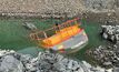 Submerged excavator while pumping water out of quarry pit.