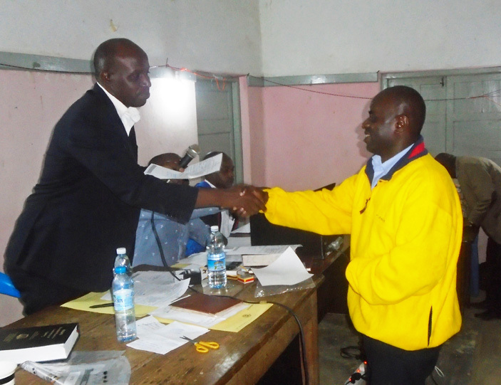  shmael twijukire the ubanda district returning officer congratulates enneth ogo iryabarema the district chairperson elect 