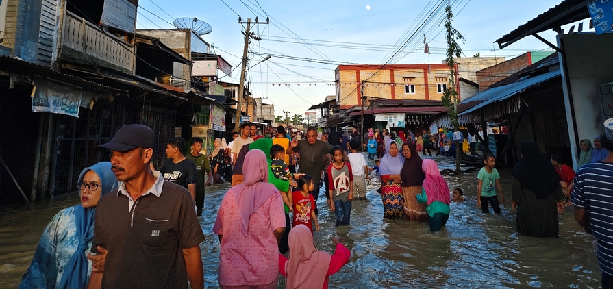 Aceh, Indonesia - November 25, 2025: Flooded neighbourhood market with residents navigating the high water.
