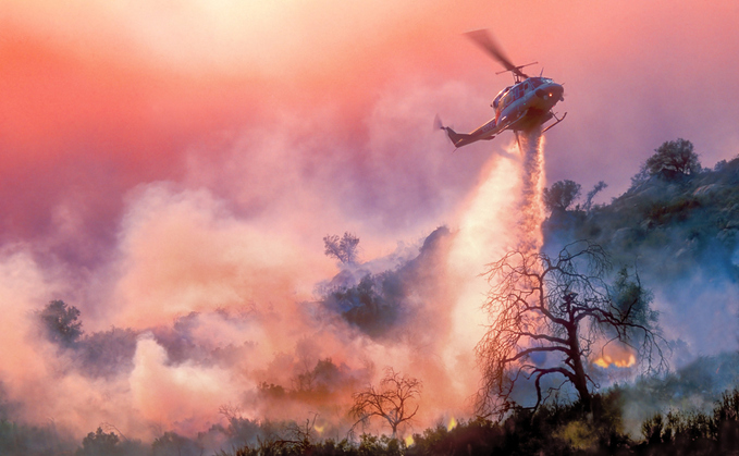 A helicopter drops water on a California wildfire | Credit: iStock