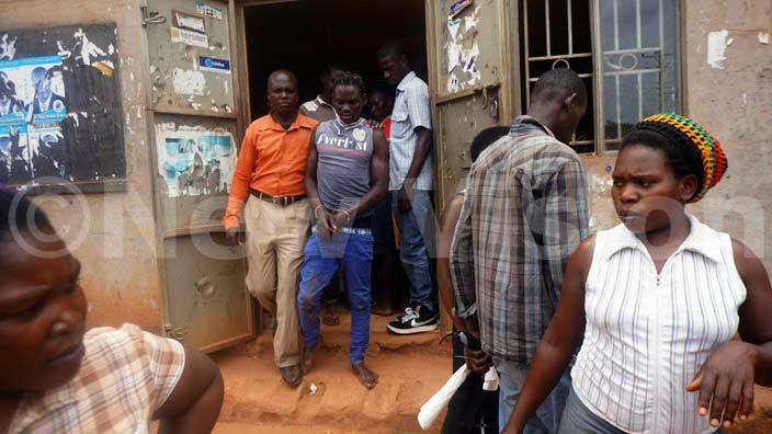 eneth adiko being whisked away by police in orange shirt attached to ikajjo police post while residents of asajja look on hoto by velyne alule