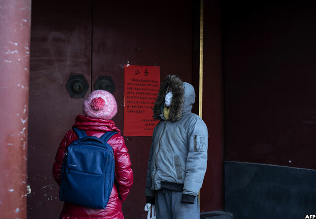 n eijing people wearing protective facemasks to help stop the spread of the deadly virus stand in front of the closed gate of the ama emple