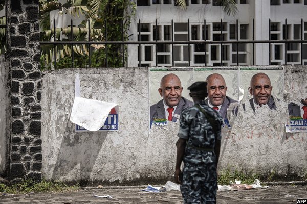  n officer stands in front of campaign posters of incumbent omoros resident and residential andidate zali ssoumani