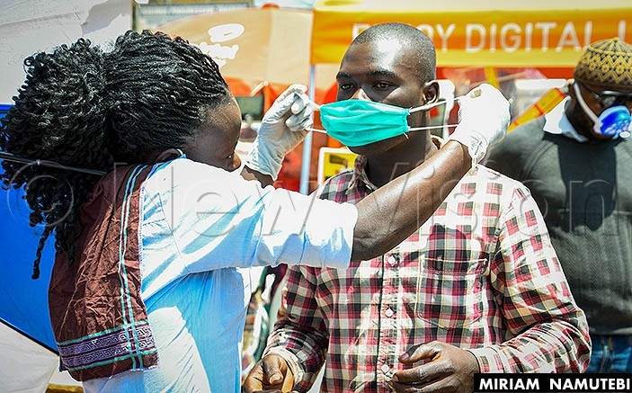  A health worker shows a man how to wear a face masks. File Photo