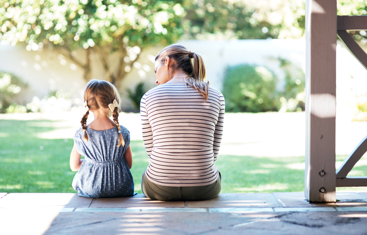 Back view shot of a young woman and child having a conversation on the porch