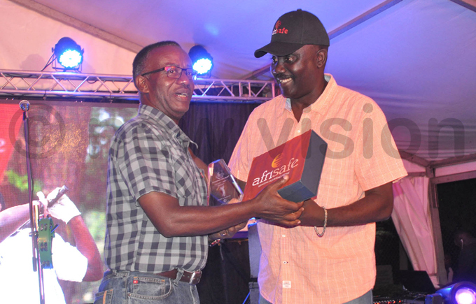 atrick agoro  receives the men roup  winners prize from ntebbe lub chairman winemanzi umubwinee hoto by ichael subuga