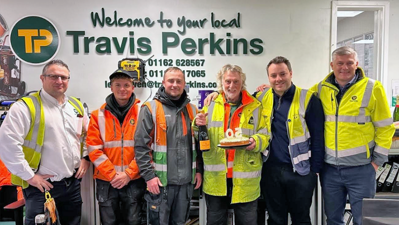Mick Ballard (holding the champagne and cake) with colleagues.