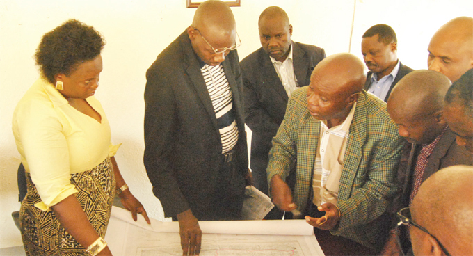 mongi left with officials from the ffice of the rime inister taking a close look at a map of yaka 1 settlement land in yegegwa he minister was in the area to solve a land dispute hotos by ogers unday