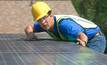 File photo: an installer places solar panels on a rooftop