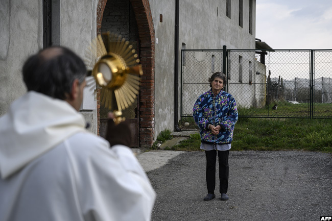  riest on resimir usic holds a crucifix and prays with a woman in anta near uneo iedmont as part of a countryside procession to bless houses against the coronavirus pandemic