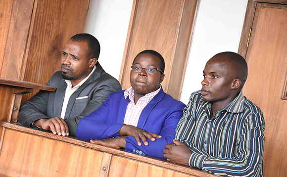 Godfrey Katongole (ku kkono), Owen Ahimbisibwe ne Abas Mpanga (ku ddyo) nga basimbiddwa mu kaguli ku kkooti ya Buganda Road. Godfrey Katongole (ku kkono), Owen Ahimbisibwe ne Abas Mpanga (ku ddyo) nga basimbiddwa mu kaguli ku kkooti ya Buganda Road.