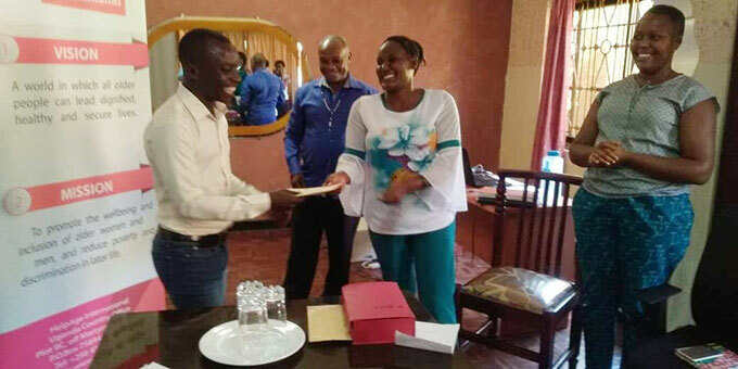  mily emigisha the national programme coordinator elp ge nternational handing over a cash prize of sh750000 to elson iiva of the ew ision at their head office in tinda