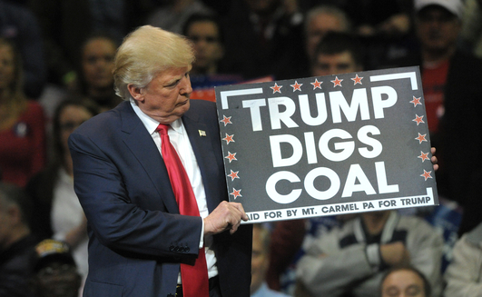 Donald Trump holds a 'Trump Digs Coal' sign during a rally in 2016.