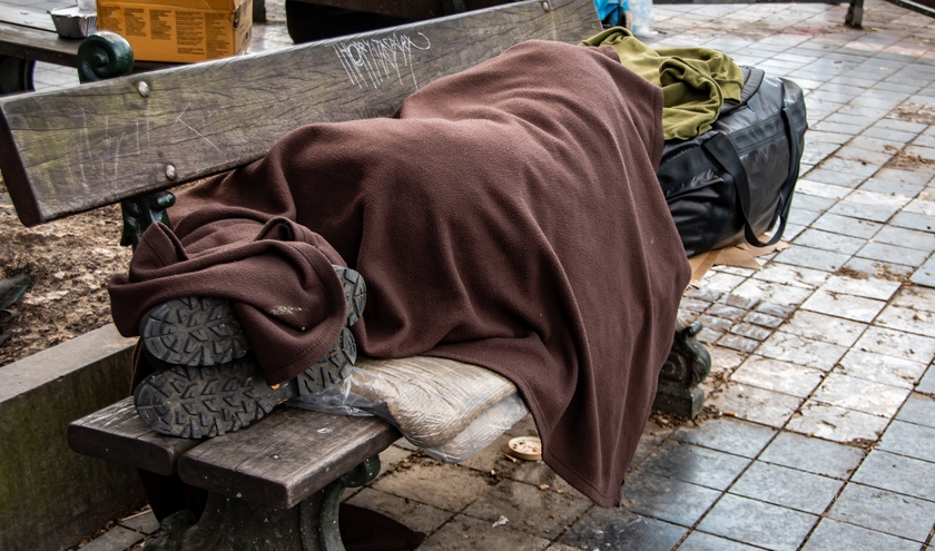 A homeless person sleeping on a wooden bench (c) Poetry Photography/Shutterstock