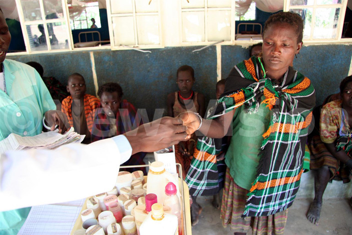   doctor at the anawat ealth entre  in anyangara ubounty of northeastern ganda otido istrict dispenses basic medicines to members of the community receiving outpatient treatment
