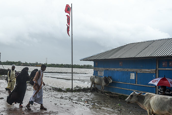  esidents walk past a great danger signal 10 flag  ahead of the expected landfall of cyclone mphan in acope of hulna district on ay 20 2020