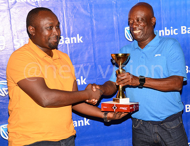  ohn asabose left receives his trophy from ky eachs tephen itamirike