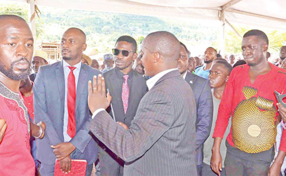 Omu ku baserikale abakuuma Omumyuka wa Pulezidenti ng’agezaako okutangira Bobi Wine (mu gaalubindi) n’abawagizi be okuyingira ekidaala mu kuziika Med Kaggwa. Omu ku baserikale abakuuma Omumyuka wa Pulezidenti ng’agezaako okutangira Bobi Wine (mu gaalubindi) n’abawagizi be okuyingira ekidaala mu kuziika Med Kaggwa.