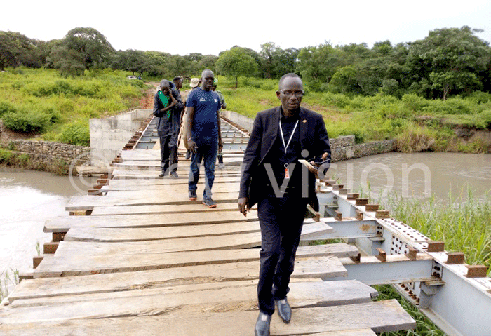  ichard ndama walks on the incomplete bridge in the background is ei forest that has been depleted