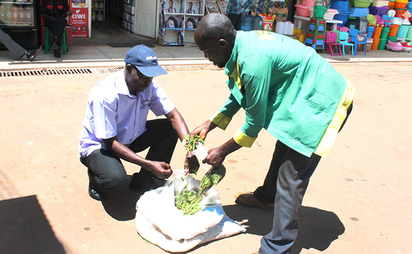 Omusuubuzi (ku ddyo) ng'aguza kasitoma enseenene Omusuubuzi (ku ddyo) ng'aguza kasitoma enseenene