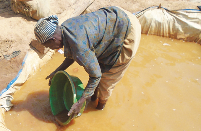 woman sieving dirt to get gold in amayingo district hotos by inah amengo