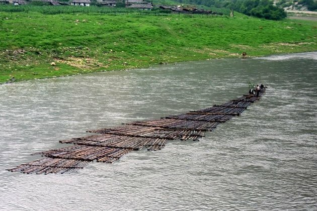 North Korean Loggers Sail Logs Down River for Meager Rations