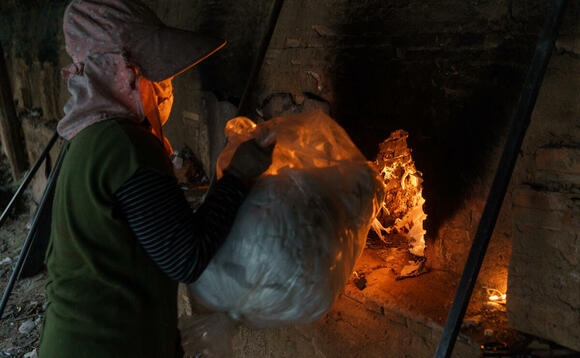 A woman loads garment products into a brick kiln located in Kandal Province, Cambodia 