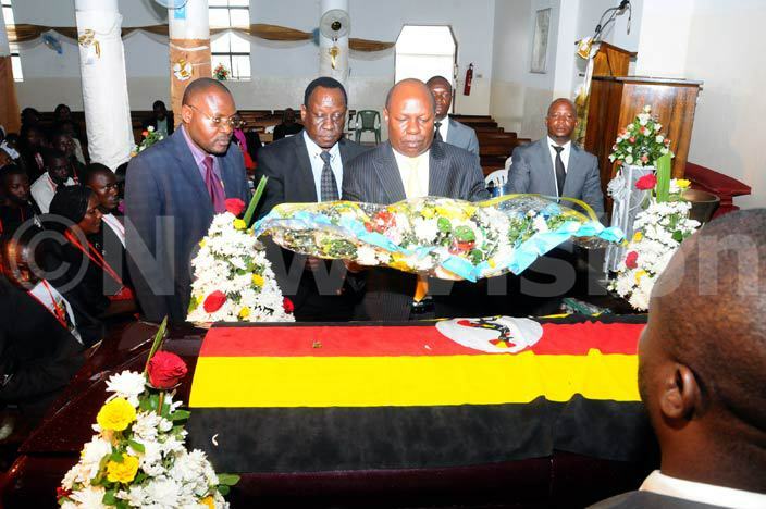tate minister for sports harles akabulindi lays a wreath on bel hairas casket during the funeral service at ll aints athedral