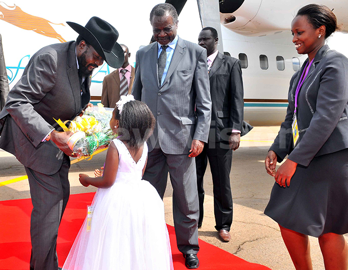 resident alva iir receives a bouquet of flowers from ochelle amugisha of ga han ursery school as  inister ggrey wori center and rotocal official ill uwagira right look on at ntebbe nternational airport on ay 11 2011 hoto by rthur intu