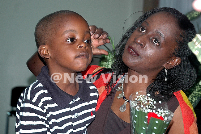  ilda awuki holds a bouquet of flowers while her son mamu looks on after arriving at ntebbe irport