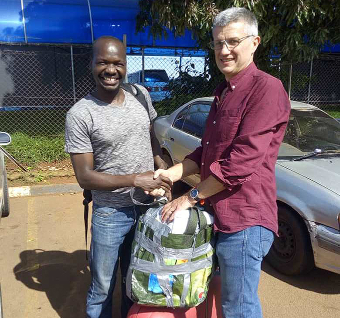 quash player ike awooya left receives the equipment from ampshire representative evin elcher at ntebbe irport ourtesy hoto