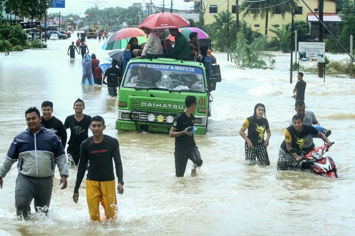  eople wade through a flooded street in alaysias northeastern town of antau anjang which borders hailand