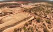 First road trains loading ore with open pit operations in the background.