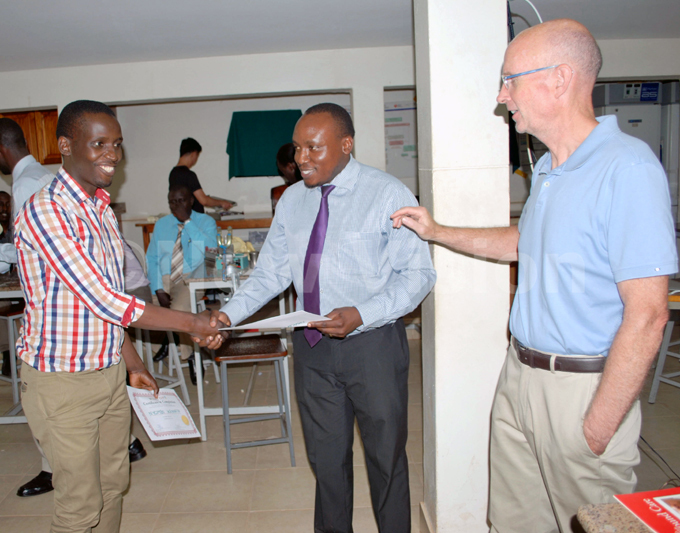 student receives a certificate of attendance from r dward ironde orthopedic surgeon at ulalgo hospital ooking on is r eter rien icture by gnes yotalengerire