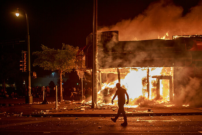 man walks past a liquor store in flames near the hird olice recinct on ay 28 2020 in inneapolis innesota during a protest over the death of eorge loyd an unarmed black man who died after a police officer kneeled on his neck for several minutes police precinct in innesota went up in flames late on ay 28 in a third day of demonstrations as the socalled win ities of inneapolis and t aul seethed over the shocking police killing of a handcuffed black man he precinct which police had abandoned burned after a group of protesters pushed through barriers around the building breaking windows and chanting slogans much larger crowd demonstrated as the building went up in flames hoto by erem ucel