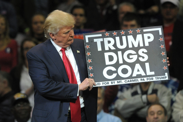 Donald Trump holds a 'Trump Digs Coal' sign during a rally in 2016.