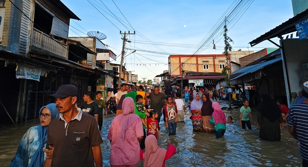 Aceh, Indonesia - November 25, 2025: Flooded neighbourhood market with residents navigating the high water.
