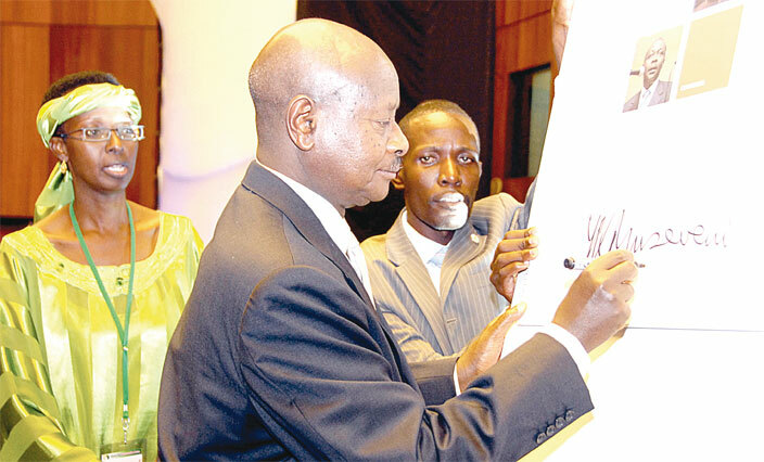  resident oweri useveni signing the frican ax dministration orum journal after the launch ampala erena otel in 2009 ooking on left is then  commissioner general llen agina
