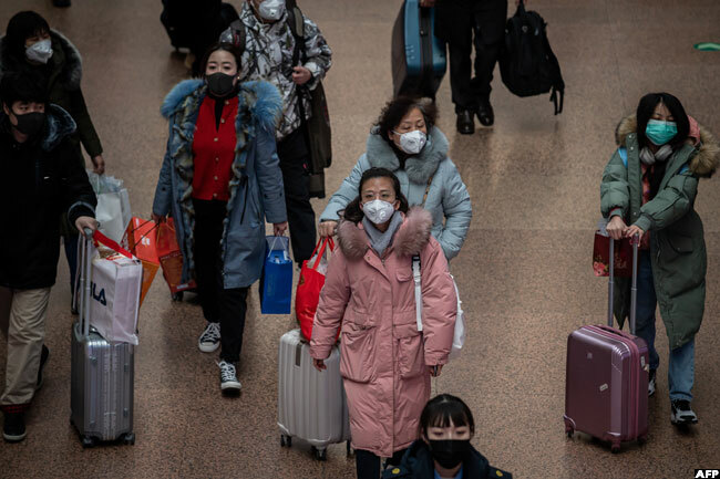  eople wearing protective masks travel for the unar ew ear holidays at the eijing est ailway tation in eijing on riday