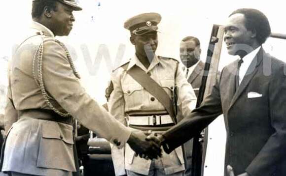Idi Amin (ku kkono) ng’abuuza ku Obote. Idi Amin (ku kkono) ng’abuuza ku Obote.