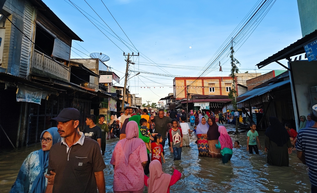 Aceh, Indonesia - November 25, 2025: Flooded neighbourhood market with residents navigating the high water.