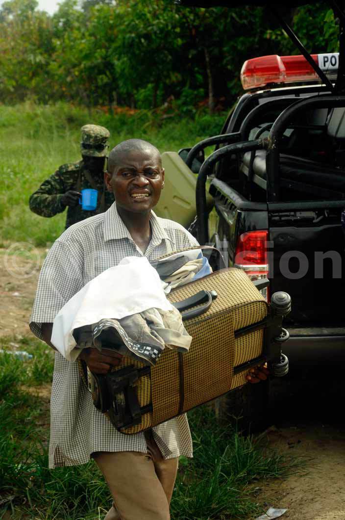   man carries his belongings after his home was attacked in undibugyo district