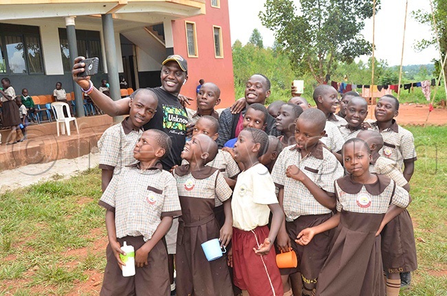  isan segawa and ulius amugera taking a selfie with the pupils of isada assion rimary chool
