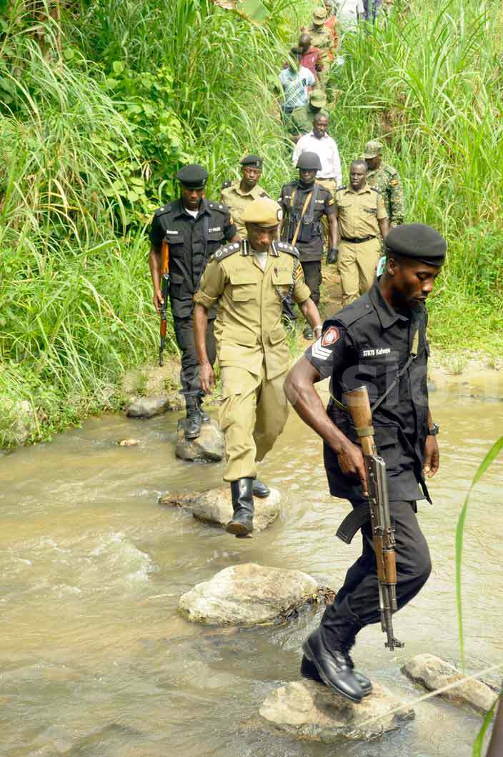  en ayihura and other police officers cross a river while in undibugyo to asess the situation after villages were attacked