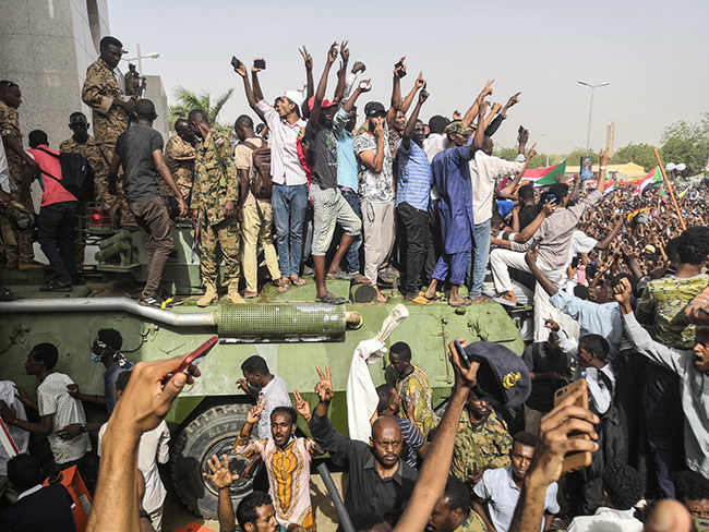  udanese antiregime demonstrators stand on an army armoured military vehicle on pril 11 2019 as they cheer and flash the sign of victory in the area around the army headquarters where protesters have held an unprecedented sitin now in its sixth day in udans capital hartoum to call on their president to step down hoto by   